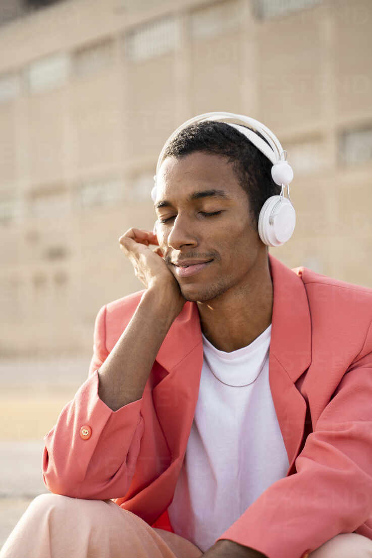 https://us.images.westend61.de/0001497595pw/young-man-sitting-with-eyes-closed-while-listening-music-through-headphones-outdoors-AFVF07895.jpg